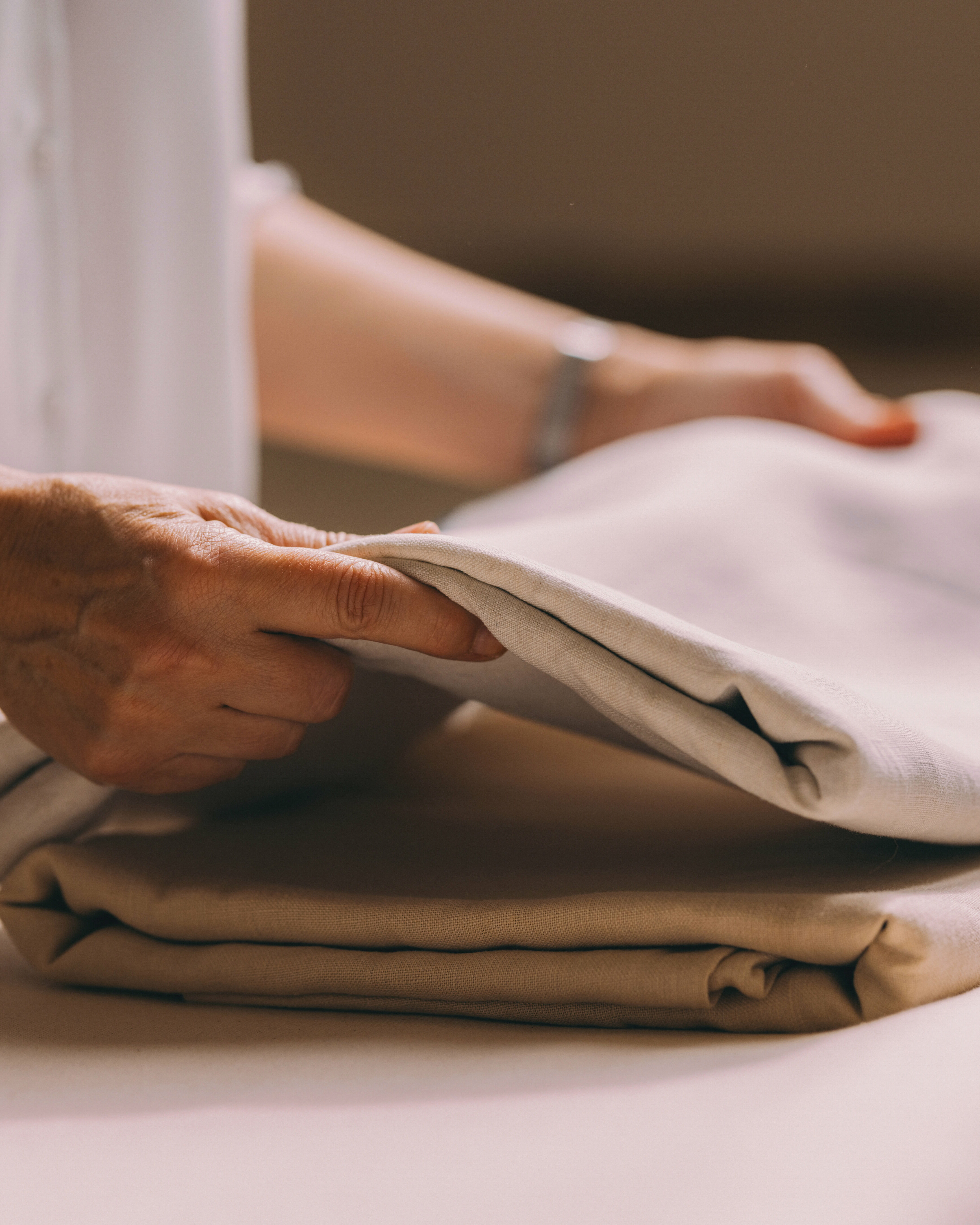 une lingère maison helya plie du linge de maison délicat